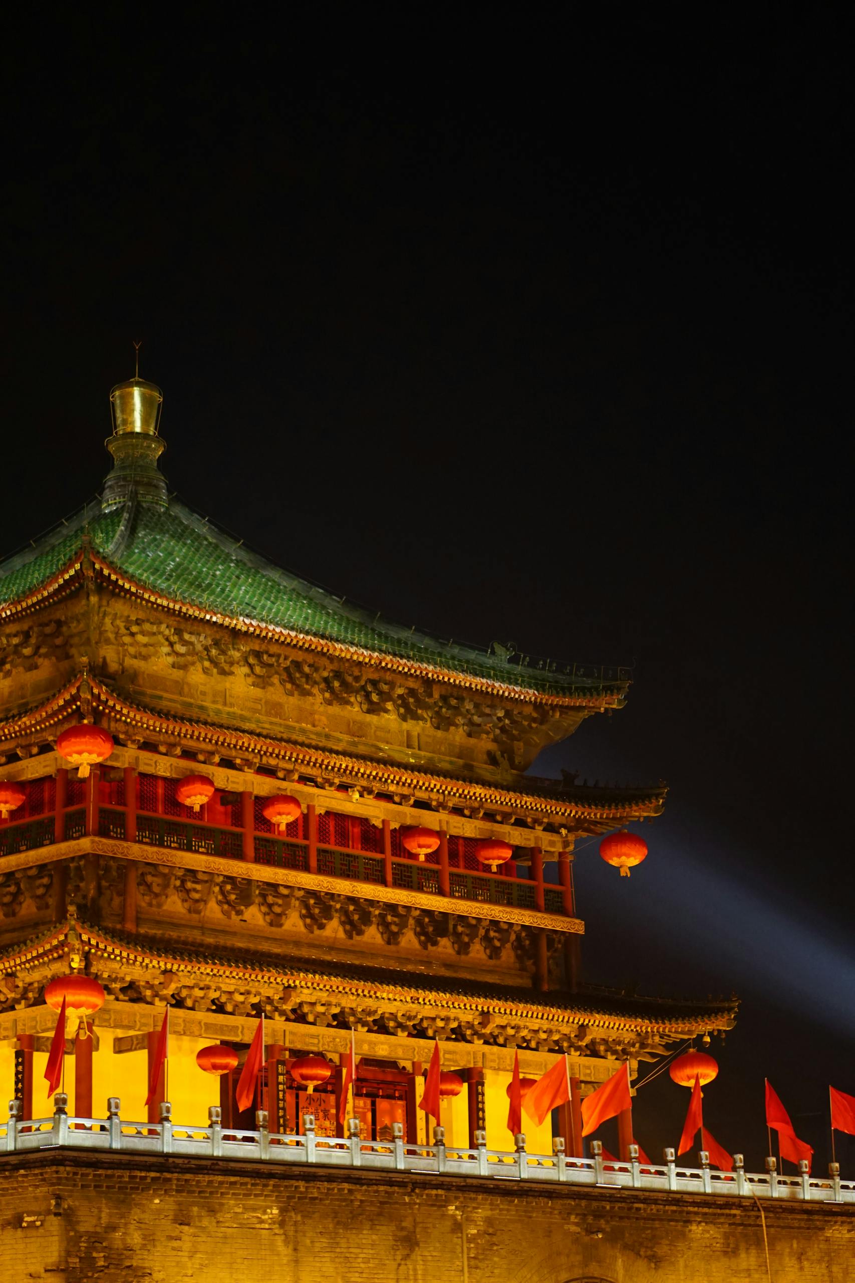A scenic view of an ancient Chinese tower illuminated by lights at night, showcasing traditional architecture.