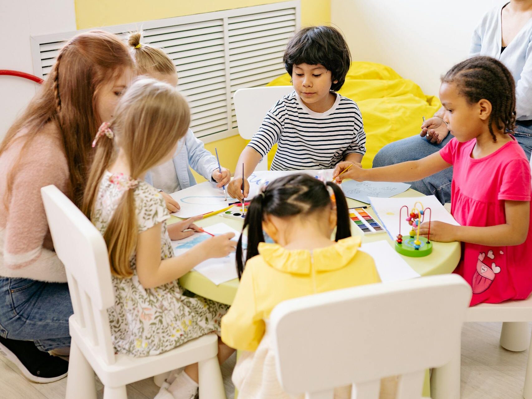 Children engaging in a creative arts and crafts session in a bright preschool classroom.